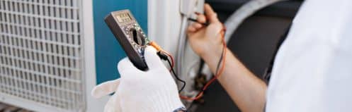 Henderson NV HVAC technician inspecting an AC capacitor on a residential outdoor unit