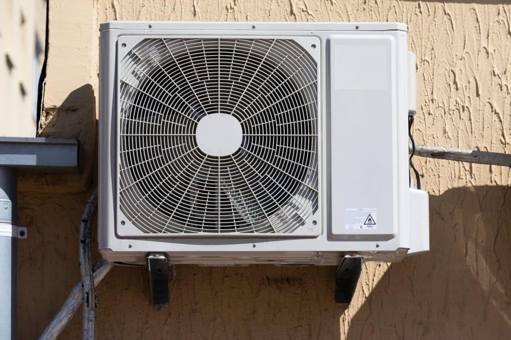 Older central AC condenser unit outside a Las Vegas home with desert landscaping