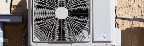 Older central AC condenser unit outside a Las Vegas home with desert landscaping