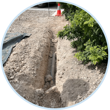 Open trench with exposed pipe during professional drain and sewer services